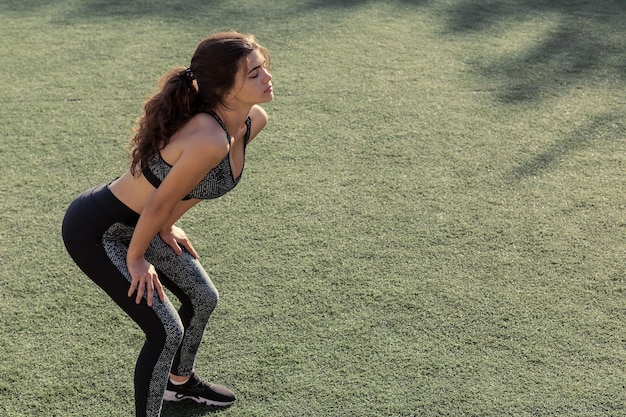 Молодая стройная спортивная девушка в спортивной одежде с принтами из змеиной кожи выполняет комплекс упражнений