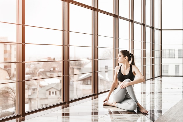 Young slim attractive woman with long hair practicing yoga indoors.