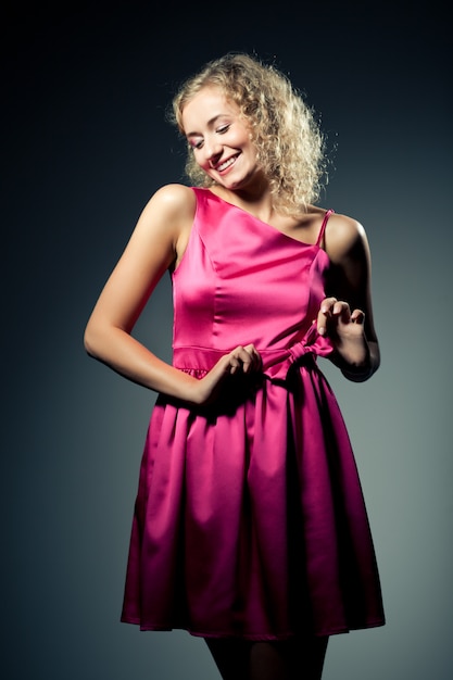 Young slim beautiful blond woman with curly hair in purple dress