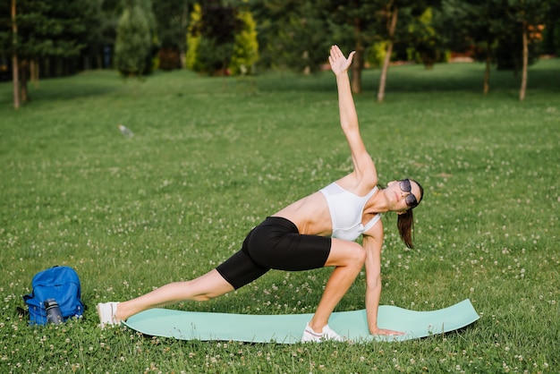 Young slim fit woman doing sport exercise outdoors in the park at the sunny day