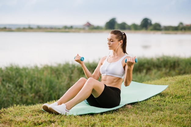 Giovane donna slim fit che fa esercizio sportivo all'aperto nel parco alla giornata di sole