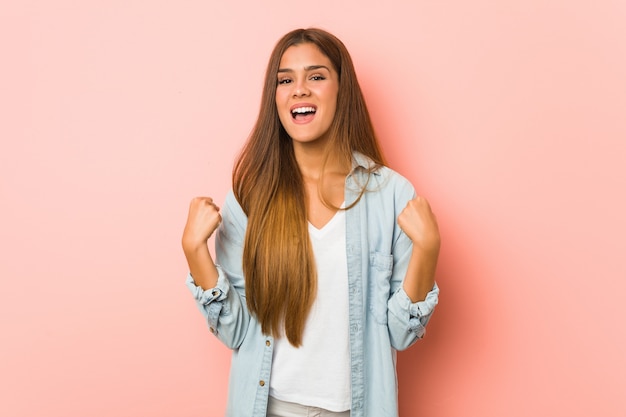 Young slim woman cheering carefree and excited. Victory concept.