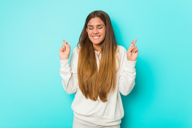 Young slim woman crossing fingers for having luck