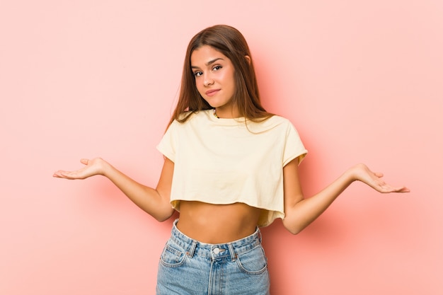 Young slim woman doubting and shrugging shoulders in questioning gesture.