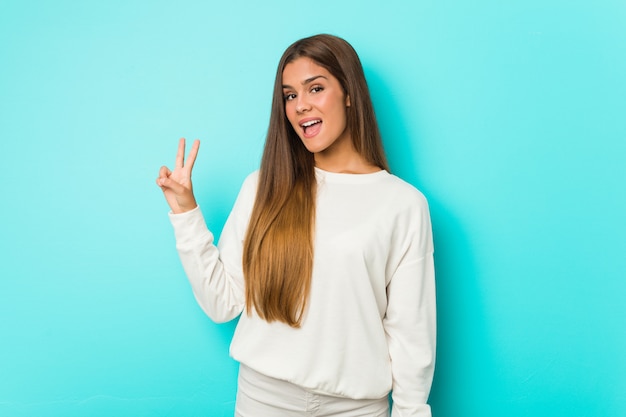 Young slim woman joyful and carefree showing a peace symbol with fingers.