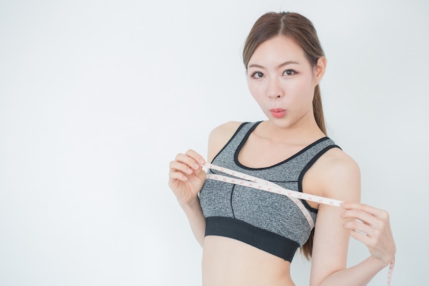 Photo young slim woman measuring her chest by measuring tape