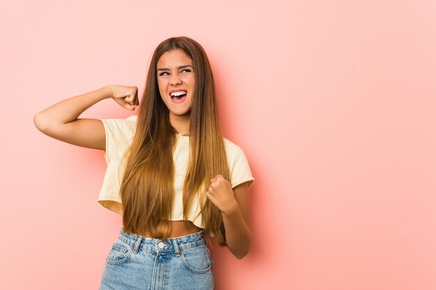 Young slim woman raising fist after a victory, winner concept.