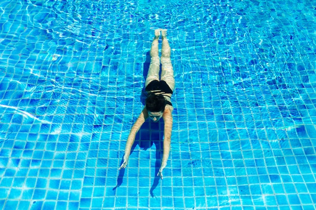 Young slim woman relaxing in swimming pool with crystal blue water