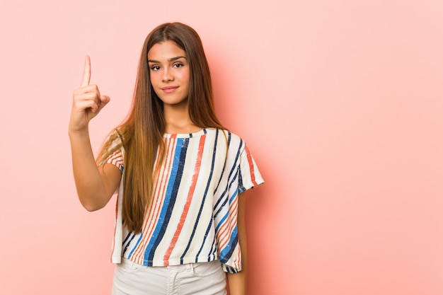 Young slim woman showing number one with finger.