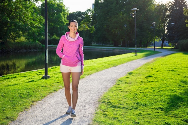 公園を歩くスポーツウェアを着た若いスリムな女性