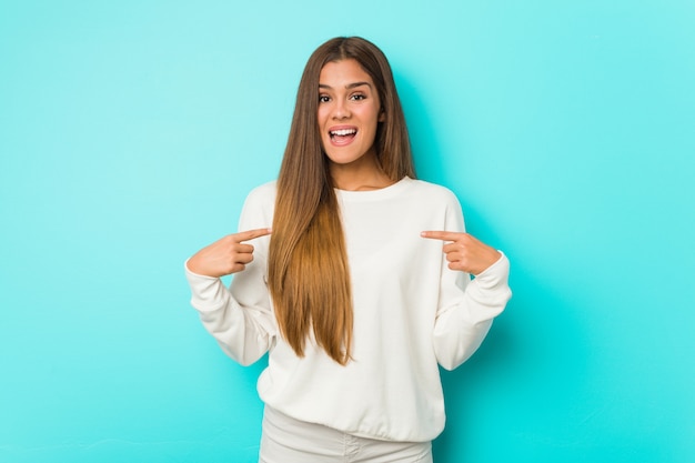 Young slim woman surprised pointing with finger, smiling broadly.