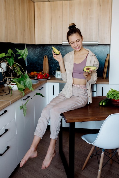 Young slim woman with bun hairstyle cooks vegetables in the kitchen in scandinavian interior style