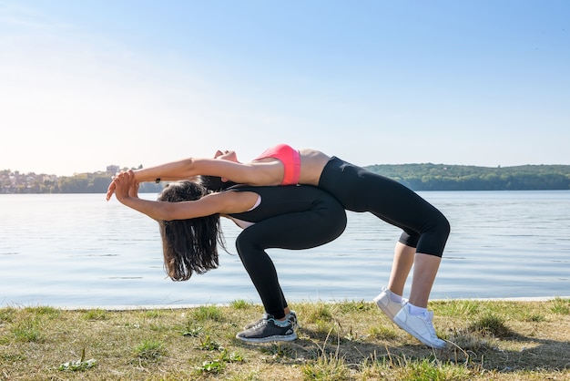 Foto giovani donne magre facendo esercizio di stretching rilassante e riscaldarsi dopo aver fatto jogging e correre nel parco vicino al lago