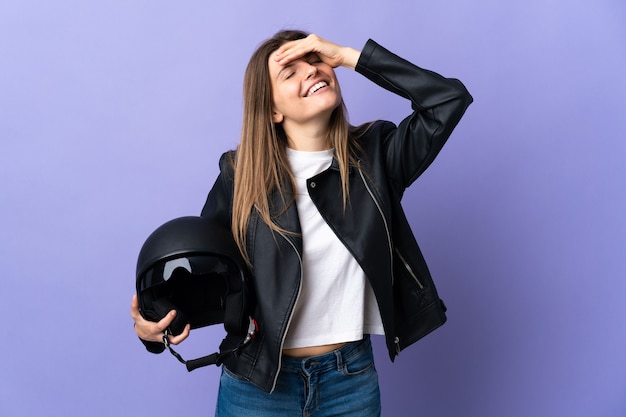 Young slovak woman holding a motorcycle helmet isolated on purple wall smiling a lot