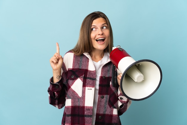 Young Slovak woman isolated on blue background holding a megaphone and intending to realizes the solution