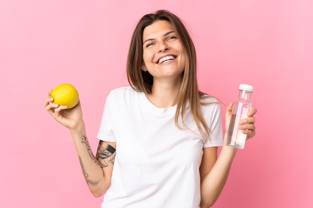 Young slovak woman isolated on pink  with an apple and with a bottle of water