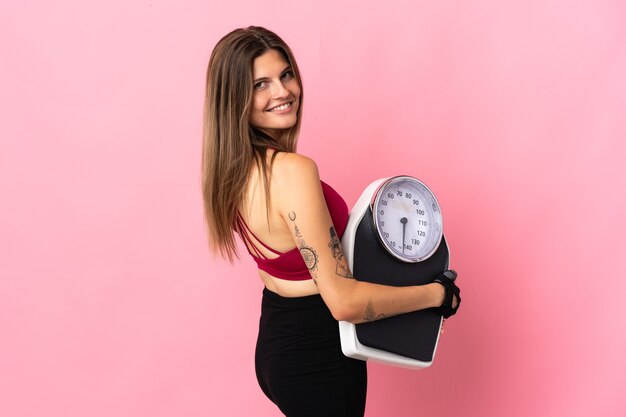 Young slovak woman isolated on pink with weighing machine