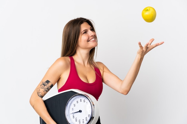 Young slovak woman isolated on white with weighing machine and with an apple