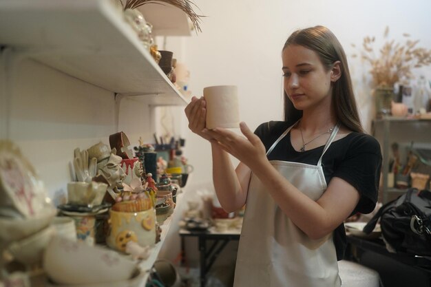 Young small business entrepreneur female with ceramics at the\
pottery workshop warehouse