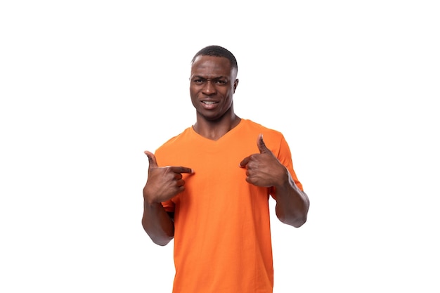 Young smart american man dressed in an orange tshirt is actively gesturing with his finger on a