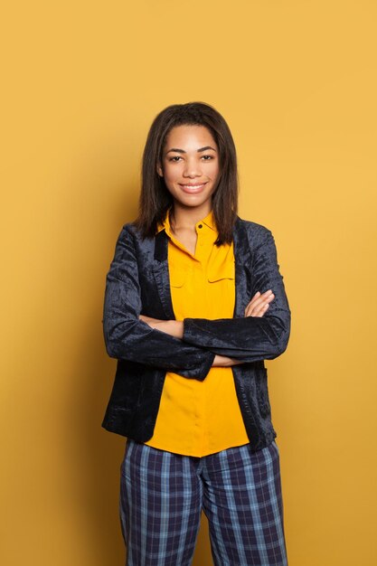 Young smart black woman with crossed arms on yellow background