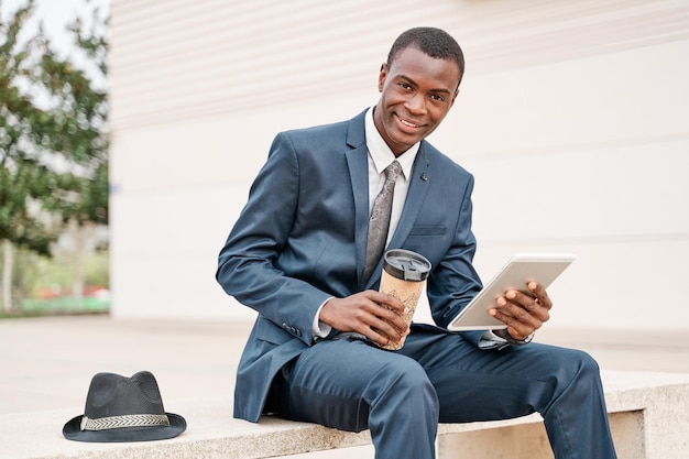 Young smart businessman using a digital tablet and analyse information on a bench in the city Working outside and Mobile office business concept