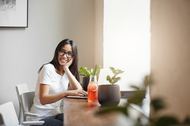 レモネードを飲み、利益を楽しんでいる近くのカフェから彼女のオンラインビジネスを実行している若くて賢い起業家