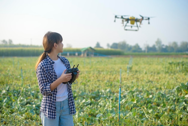 A young smart farmer controlling drone spraying fertilizer and\
pesticide over farmland