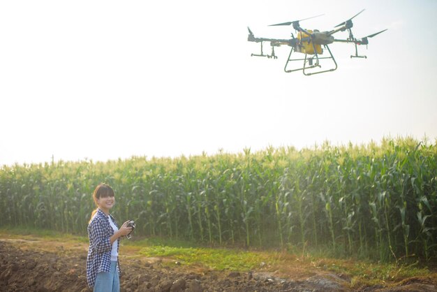 A young smart farmer controlling drone spraying fertilizer and\
pesticide over farmland