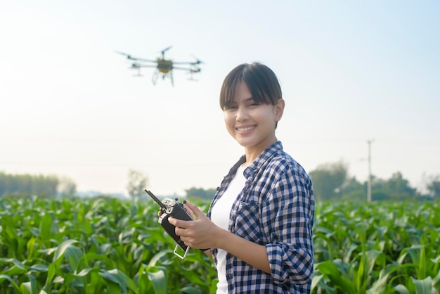 Молодой умный фермер, управляющий дронами, распыляющими удобрения и пестициды над сельскохозяйственными угодьями