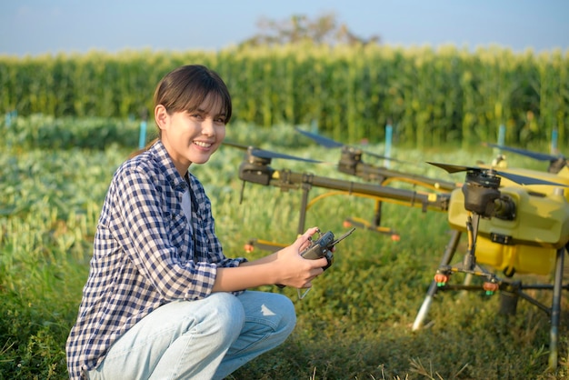Un giovane agricoltore intelligente che controlla i droni che spruzzano fertilizzanti e pesticidi sui terreni agricoli