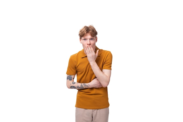 Photo young smart guy with red hair stands thoughtfully on a white background with copy space