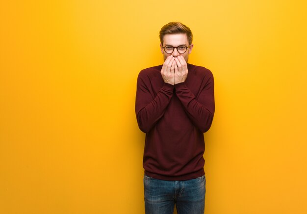 Young smart man laughing about something, covering mouth with hands