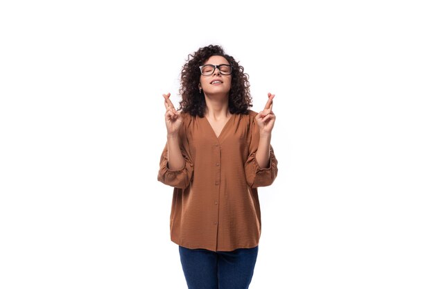 Photo young smart slim woman with curly haircut dressed in brown blouse crossed her fingers