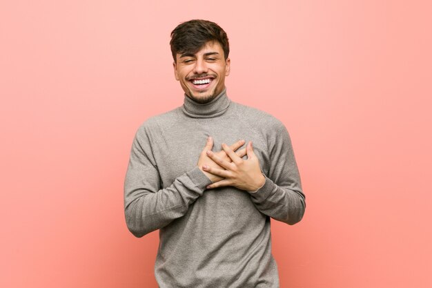 Young smart student man laughing keeping hands on heart, concept of happiness.