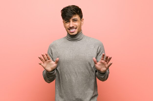 Young smart student man rejecting someone showing a gesture of disgust