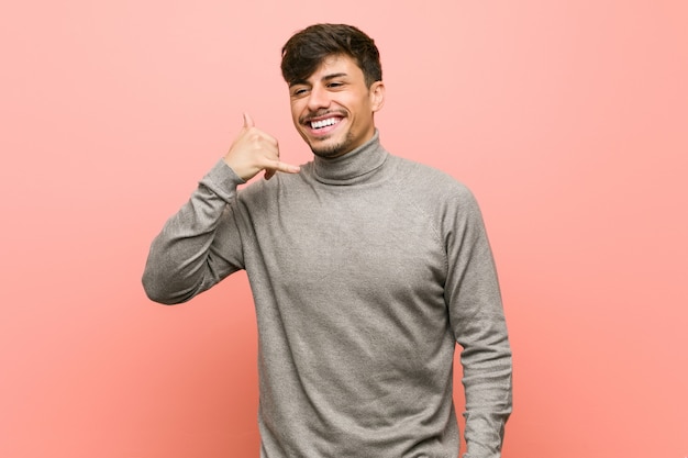 Young smart student man showing a mobile phone call gesture with fingers.