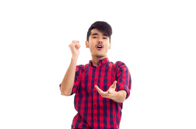 Young smartlooking man with dark hair wearing in red plaid shirt on white blackground in studio