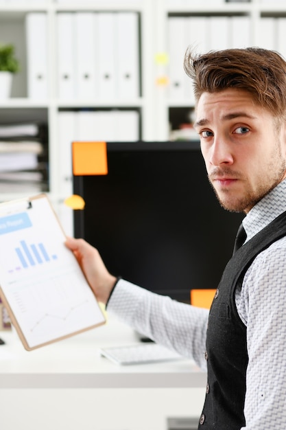 Giovane uomo di sorriso al ritratto del primo piano dell'area di lavoro dell'ufficio.