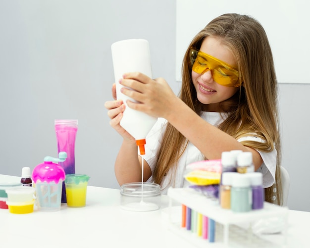 Foto scienziato della giovane ragazza di smiley che produce la melma in laboratorio