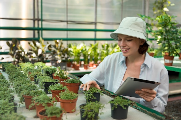 Young smiley woman working in a greenhouse