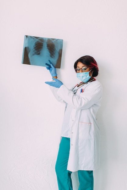 Young smiling African American doctor in medical mask holding patient's x-ray