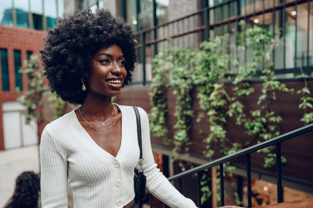 Young smiling african woman poses near stairs in the city