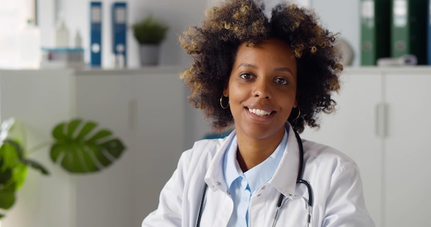 Young smiling AfricanAmerican woman doctor sitting in clinic office