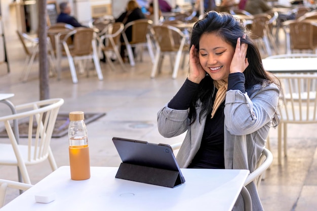 Молодая улыбающаяся азиатская деловая женщина с помощью планшета смотрит онлайн-курс электронного обучения веб-семинар