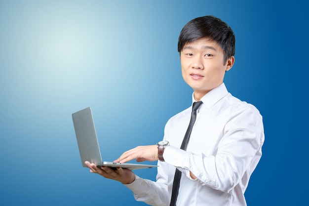 Молодой улыбающийся азиатский бизнесмен, держащий ноутбук
