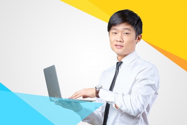 Young smiling asian businessman holding laptop