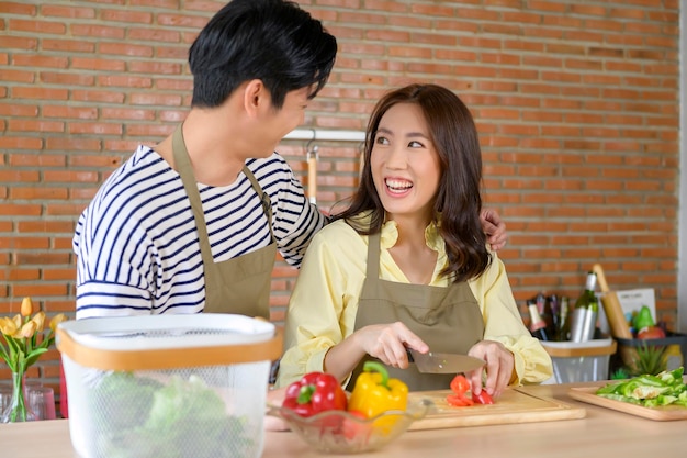 Young smiling asian couple wearing an apron in the kitchen room cooking concept