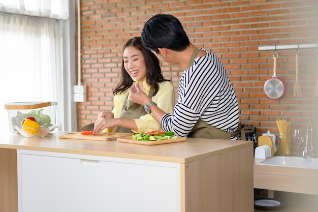 Young smiling asian couple wearing an apron in the kitchen room cooking concept