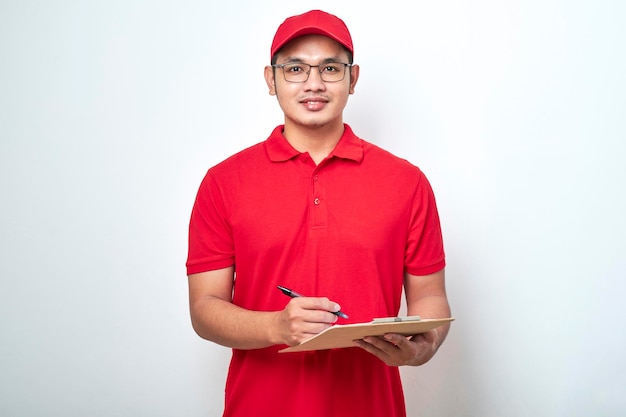 Young smiling asian delivery man in red uniform and cap holding clip board